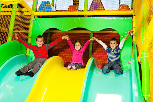 three children on a slide at the indoor playground