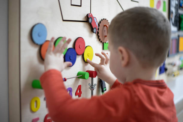 three years old boy playing on the busy board at his psychotherapy session.
